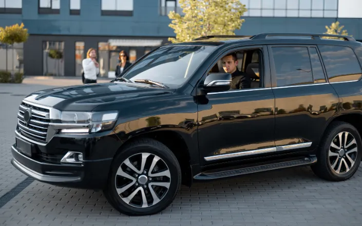 Professional chauffeur opening the door of a luxury SUV in Oslo